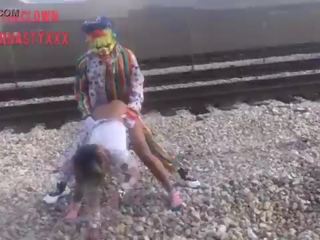 Clown scopa giovane signora su treno tracks